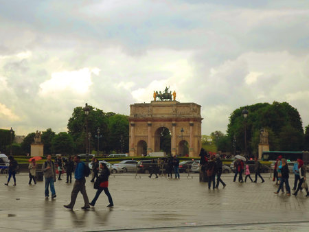 People walking near the Triumphal Arch (Arc de Triomphe du Carrousel) at Tuileries in a rainy day. Paris, Franceのeditorial素材