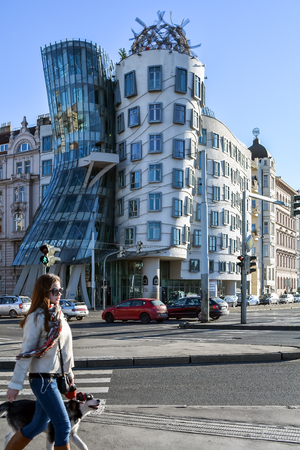 Young lady with a dog passing by famous Dancing House in Prague, Czech Republicのeditorial素材