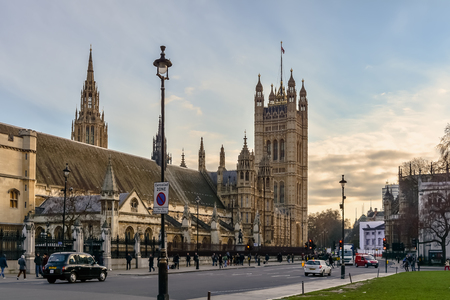 Central and Victoria Towers of The Palace of Westminster with the bronze statue of Oliver Cromwell and classic British taxicab in shot.のeditorial素材