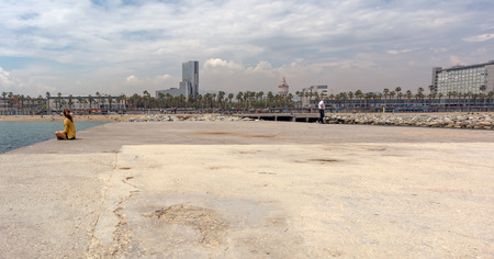 People are sitting and walking on Barceloneta breakwater. View on Barceloneta beach from Gas breakwater.のeditorial素材