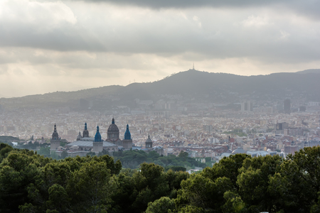 View to Barcelona city from the Montjuic hill in cloudy evening with The Palau Nacional (National Palace) Renaissance domes in the foreground. Barcelona evening skyline under cloudy sky.の写真素材