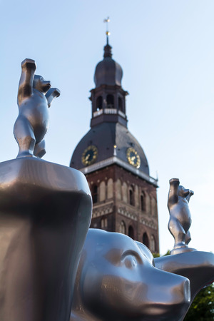 Riga, Latvia - July 15, 2018: 'Respect for life' bear at United Buddy Bears international art exhibition (Artists: A. Oetker, A. Haufe) with Riga Cathedral tower in background.のeditorial素材