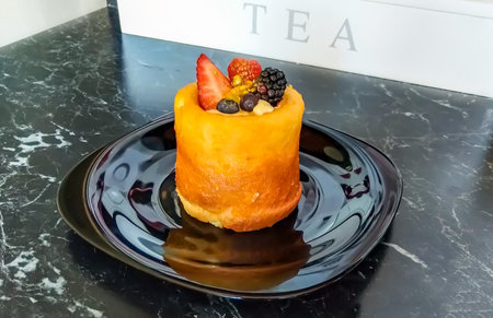 Mini cake decorated with fresh strawberry, raspberry, blackberry, golden dust, and summer berries on...