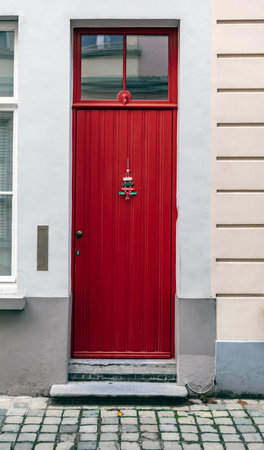 Vintage red front door decorated with Christmas tree ornament shot in Bruges, Belgium. Old red door with window at the top.の写真素材