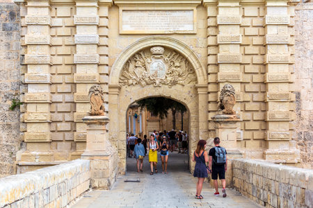 Mdina, Malta - August 31, 2019: Tourists walking through Baroque portal of Mdina Gate, also known as...