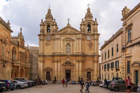 Mdina, Malta - August 31, 2019: Tourists wandering at St. Paul's Square before entrance to St Paul's Cathedral, built in Baroque style, with influences from native Maltese architecture.のeditorial素材