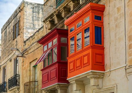Two traditional Maltese enclosed wooden balconies painted in red and orange in Cospicua (Bormla), Malta. Authentic Maltese urban scene.の写真素材