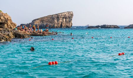 Comino, Malta - September 3, 2019: People bathing in the cyan water of Blue Lagoon. Blue Lagoon is a picturesque bay, with a brilliant white, sandy base, and with shallow, azure-coloured water.のeditorial素材