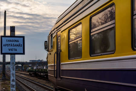 Riga, Latvia - October 20, 2019: Suburban passenger train at the station platform in the evening, with girl face in the window and signのeditorial素材