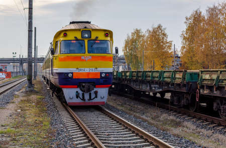Riga, Latvia - October 20, 2019: Suburban passenger train drives off from the station platform. Yellow-blue back of train at the railway station in Riga. Transportation concept.のeditorial素材
