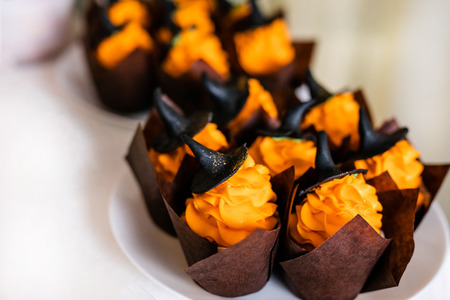 Cupcakes with orange cream and sweet black hats on the candy bar for the celebration of Halloween.の写真素材