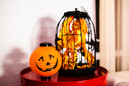 Decorative paper pumpkin lantern and cage with orange toy bird. Decor for he celebration of Halloween.の写真素材
