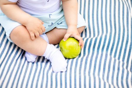 Little baby's fingers holding yellow pearの写真素材