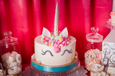 Sweet table and big unicorn cake for baby girl first birthday. Candy bar with a lot of different candies and sweet cakesの写真素材