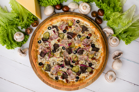 High angle view of tasty pizza on wooden table surrounded by vegetables, mushrooms and cheeseの写真素材