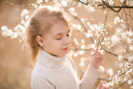 Blonde girl in the blossom garden. Spring background with white flower.の写真素材