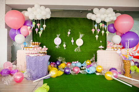 Birthday party concept, decorations for sweet party. Huge number one, table with sweets and desserts, cloud from balloons and ice-creams, a lot of colored balloons and big candy toys.の写真素材