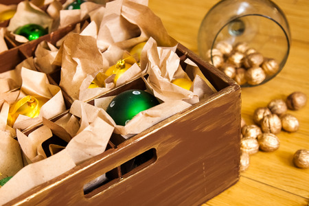 Wooden box with green balls and golden toys for the decor, golden nuts on the floor. Christmas and New Year.の写真素材