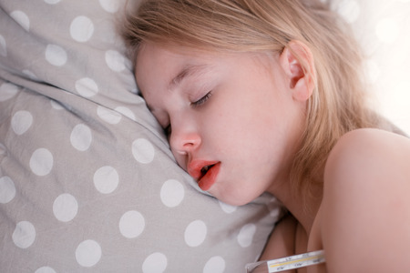 Blonde sleeping child with clinical thermometer.の写真素材