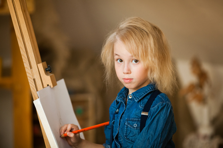 little blonde girl lying on the floor and drawing with colored pencilsの写真素材
