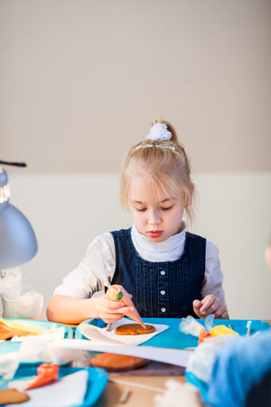 The girl learns to decorate gingerbread with sugar icing.の写真素材