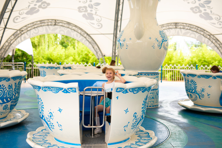 Blonde boy in the straw hat and big glasses and girl in white and blue dress in the entertainment park.の写真素材