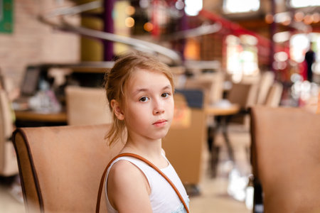 Blonde girl in white and blue dress having lunch in the restaurant.の写真素材