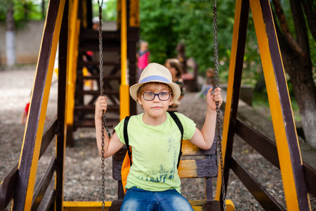 Blonde boy with hat and glasses with special lens playing in the playground.の写真素材
