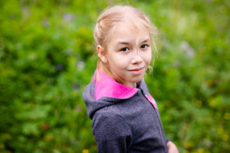 Cute blonde girl in the mountains wearing warm gray jacket.