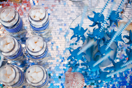 Blue cake pops funny octopuses shared on the glass round plate and jars whith marshmallow. Summer candy bar on the party, birthday.の写真素材