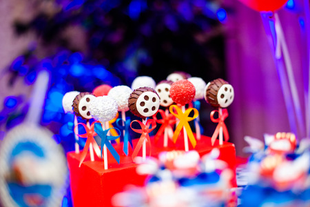 Candy bar on boy's birthday party with a lot of different candies, popcorn, beverages and big cake standing on a barrel. Decorated in bright colors. Hot wheels, cars or racing theme. Summer, outdoor.の写真素材