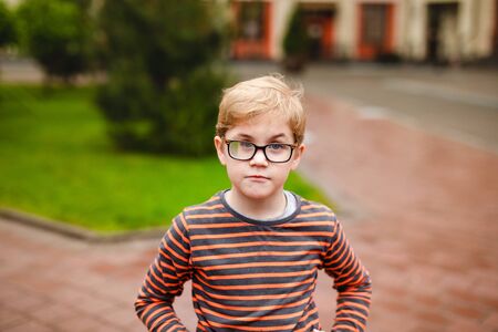 Strong, smart and funny little boy playing outdoors, wearing eyeglasses .の写真素材