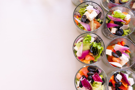 Little glasses with fresh salads, eggs, salmon and cucumbers standing on white table. Free space for text. White backgroundの写真素材