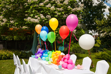 Birthday table with rainbow balloons. Summer holiday in the park.の写真素材