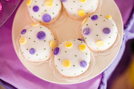 Candy bar for the birthday. White round cakes with big yellow and purple dots and with small green dots. Top viewの写真素材