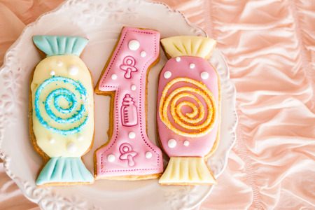 Candy bar for the first birthday for little baby girl or boy. Sweet table and nice pink biscuits on the white plate. Gingerbread number-shaped oneの写真素材