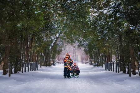 Boy and girl sledding in the snowy yard. Winter backgroundの写真素材