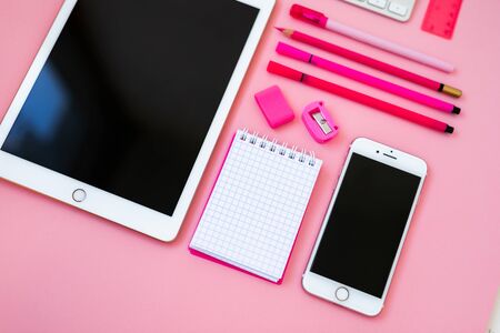 Mobile phone and notebook in a cage on a pink backgroundの写真素材