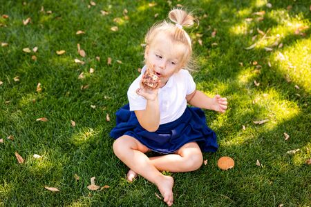Cute adorable Caucasian toddler baby girl sitting and eating berries fruits. Funny child in park having healthy snack meal. Summer delicious tasty finger food for kidsの写真素材
