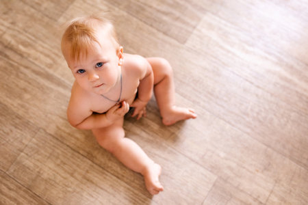 Portrait of a one year old child sitting on the wooden floor. Pretty little boy at homeの写真素材