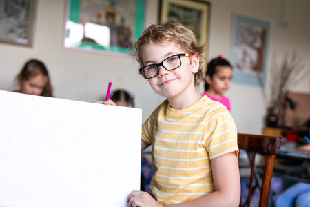 Blonde boy with glasses drawing. Group of elementary school pupils in classroom on art class. Russia, Krasnodarの写真素材