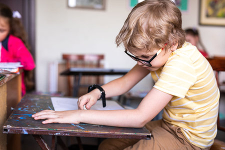 Portrait of cute boy with sketch pen and paper at desk in classroom. Russia, Krasnodar