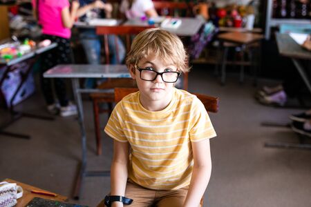 Portrait of cute boy with sketch pen and paper at desk in classroom. Russia, Krasnodarの写真素材