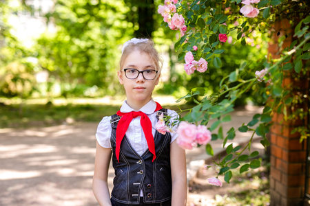 A schoolgirl in a white blouse with a red tie, with a bow in the class. Back to school concept.