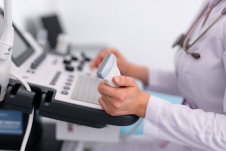 Young blonde doctor working on ultrasound machine in new clinic. Helthcare concept.の写真素材