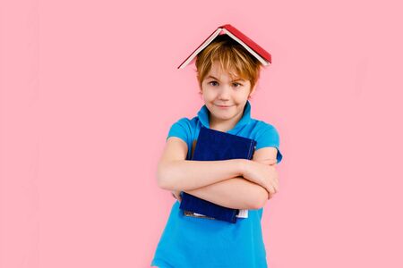Blonde boy in t-shirt reading a book thirsty for knowledge on pink backgroundの写真素材