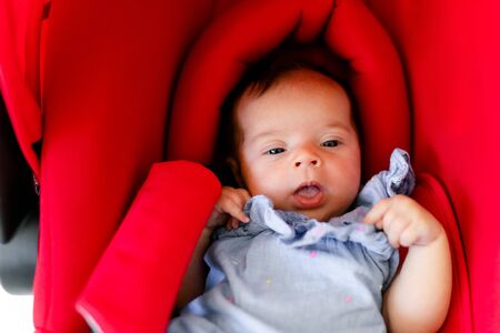 Newborn baby boy sleeping in modern car seat. New born child traveling by car. Child safety on the road. Safe way to travel with young kids. Fastened seat belts in a vehicle. Trip with an infantの写真素材