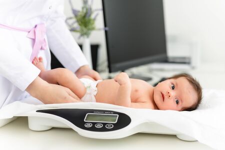 Close-up of a doctor checking weight of cute little baby. Healthcare concept.の写真素材