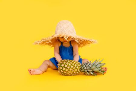 Funny little girl dressed in a red swimsuit, big hat and sunglasses heart sunbathes on a sun lounger.の写真素材