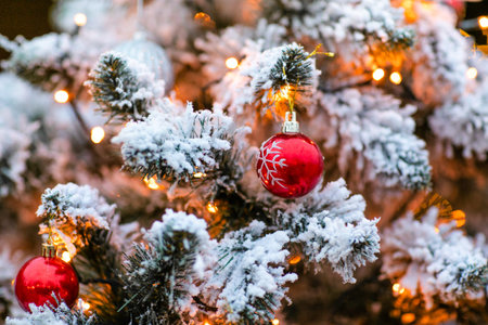 Fir tree decorated with snow and toy red glass ball and light bulbs for Christmas and New Year...